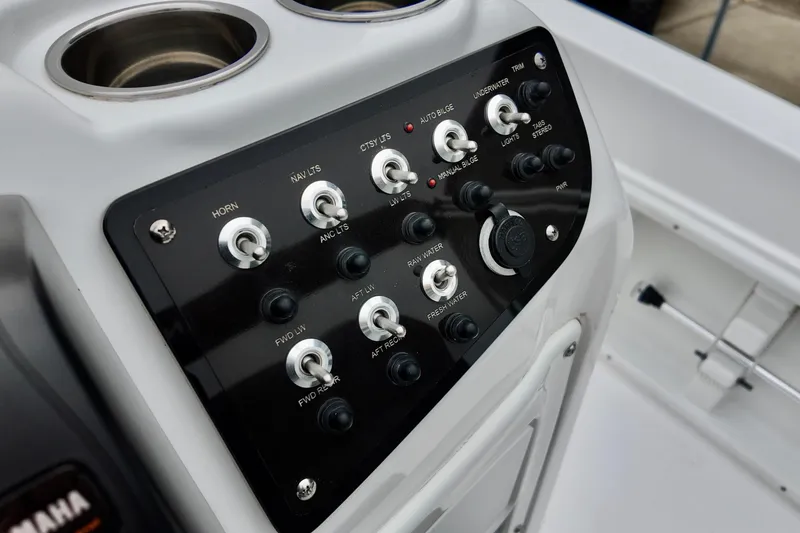 Slide: The Image of Control panel of 2025 NauticStar 211 Hybrid boat with various switches and cup holders. - 5