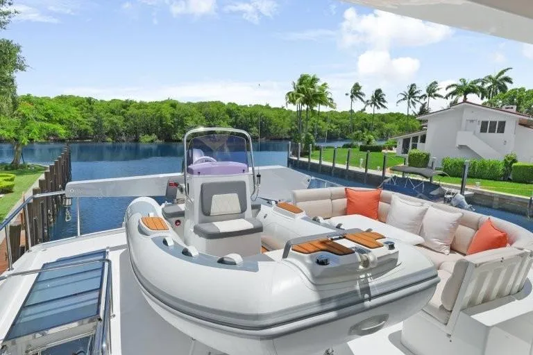 Slide: The Image of 2003 Hargrave Sky Lounge yacht with inflatable boat and seating area, docked by a scenic waterfront. - 80