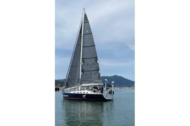 Slide: The Image of Sailboat "Blue Jacket 40" from 2015 on calm water with mountainous backdrop. - 54