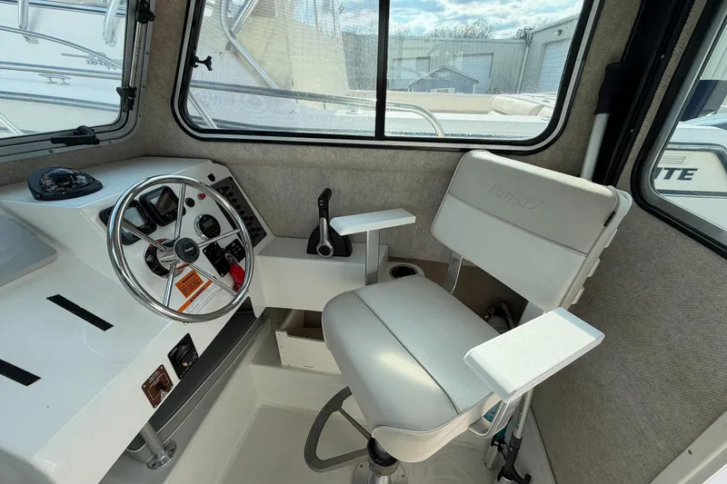 Slide: The Image of Interior of a 2015 Parker 2120 boat, featuring steering wheel and captain's chair. - 13