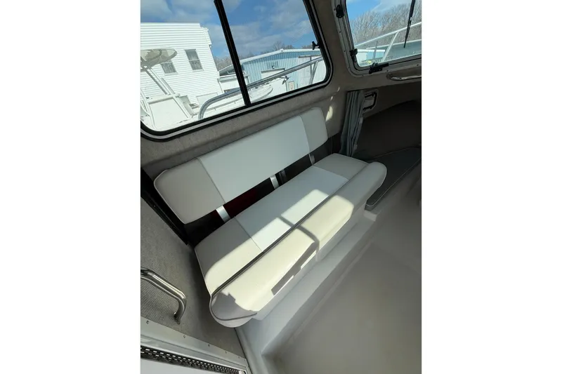 Slide: The Image of Interior seating of a 2015 Parker 2120 boat, featuring white cushioned bench. - 9