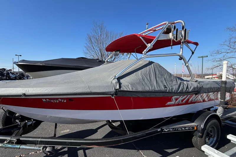 Slide: The Image of 2006 Nautique Ski Nautique 206 boat with cover on trailer, under clear blue sky. - 25