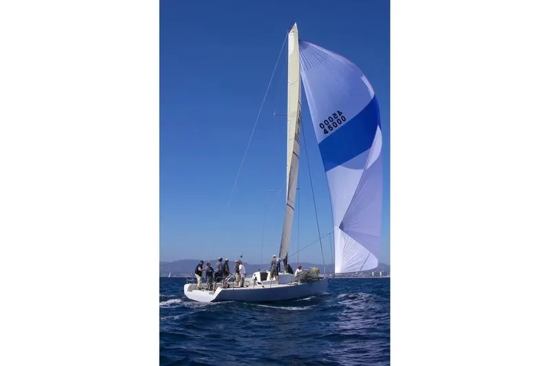 Slide: The Image of Sailboat Antrim 40 with blue spinnaker sailing on open water under clear sky. - 26