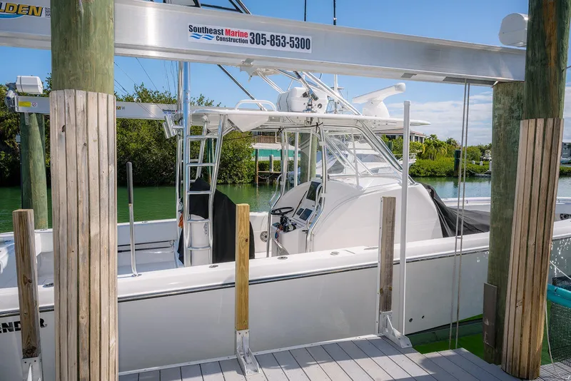 Slide: The Image of 2022 Contender 39 Fisharound boat docked at marina with lush greenery background. - 2