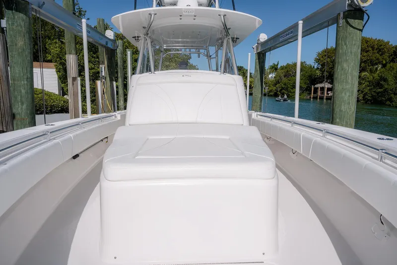 Slide: The Image of 2022 Contender 39 Fisharound boat with white seating, docked by a scenic waterway. - 26