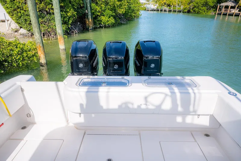 Slide: The Image of 2022 Contender 39 Fisharound with triple outboard engines in a serene waterway. - 28