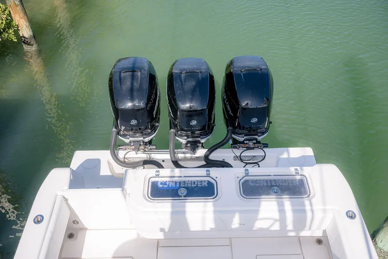 Slide: The Image of Triple outboard engines on a 2022 Contender 39 Fisharound boat, docked in clear water. - 43