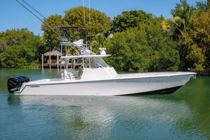 Slide: The Image of 2022 Contender 39 Fisharound boat on calm water, surrounded by lush greenery. - 53