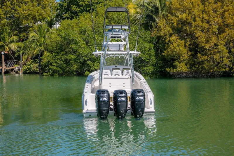 Slide: The Image of 2022 Contender 39 Fisharound boat with triple 400 horsepower engines in a lush, tropical setting. - 56