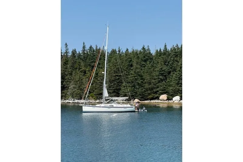 Slide: The Image of 2021 Hallberg-Rassy 40C sailboat anchored near forested shoreline. - 11