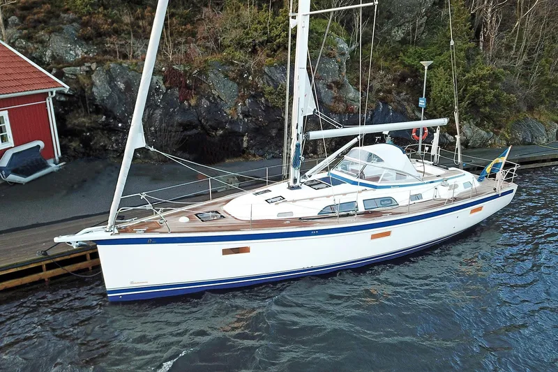 Slide: The Image of 2021 Hallberg-Rassy 40C sailboat docked by rocky shoreline. - 12