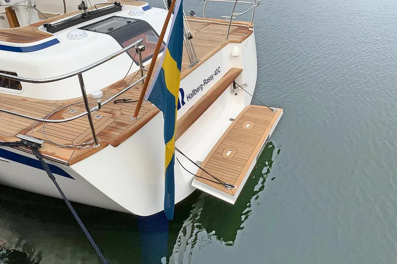 Slide: The Image of 2021 Hallberg-Rassy 40C yacht with wooden deck and Swedish flag on calm water. - 15