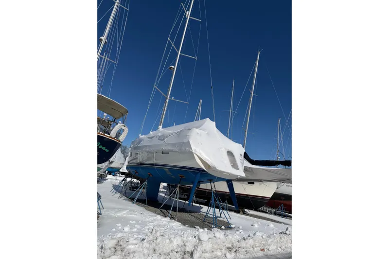Slide: The Image of Hallberg-Rassy 40C 2021 sailboat covered in snow, stored on land with other boats. - 20
