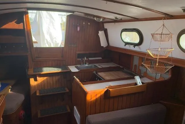 Slide: The Image of Interior of a 1978 Rafiki 35 sailboat with wooden finishes and compact kitchen area. - 13