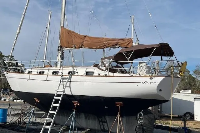 Slide: The Image of 1978 Rafiki 35 sailboat on dry dock with brown sails and ladder. - 4