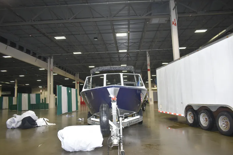 Slide: The Image of 2026 KingFisher 16 Falcon boat displayed indoors, rear view with motor and trailer. - 4