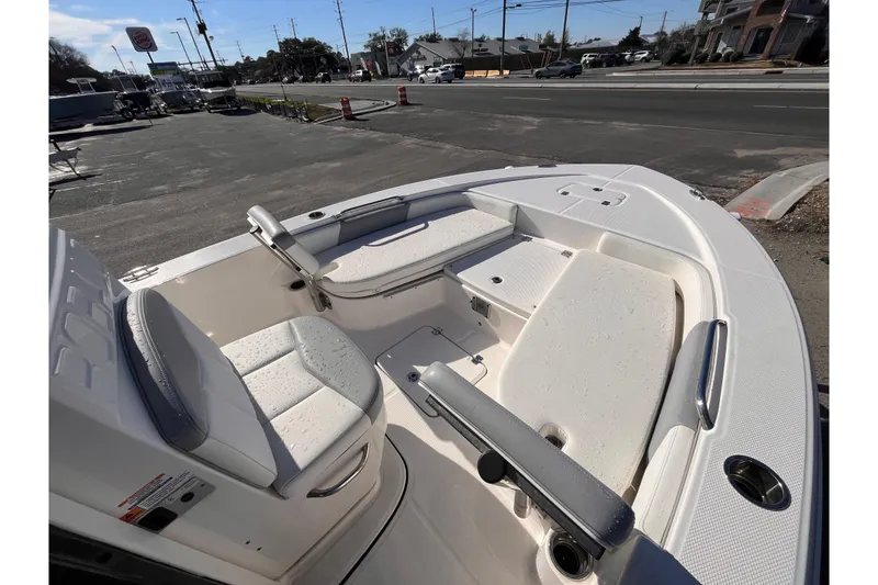 Slide: The Image of 2022 Robalo 226 Cayman boat interior with seating and storage, parked near a road. - 11