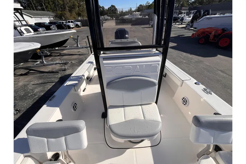 Slide: The Image of 2022 Robalo 226 Cayman boat interior with seating and console, parked outdoors. - 12