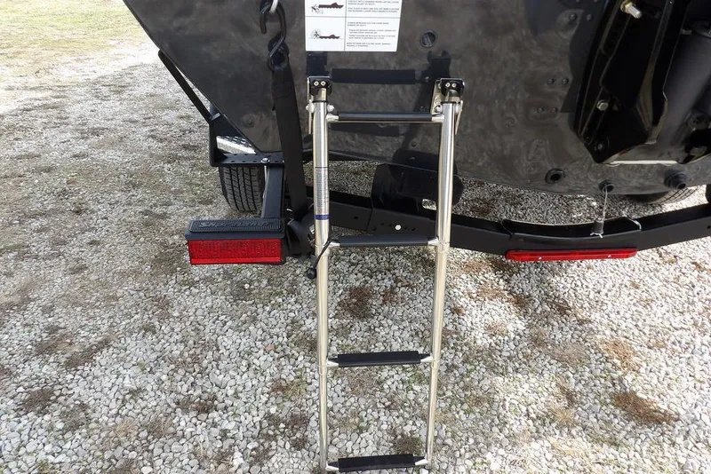 Slide: The Image of Rear view of 2026 Lund 1975 Renegade boat with ladder on gravel surface. - 37