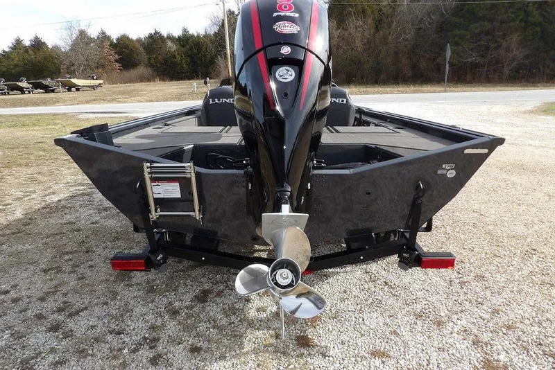 Slide: The Image of 2026 Lund 1975 Renegade boat with outboard motor, parked on gravel. - 5