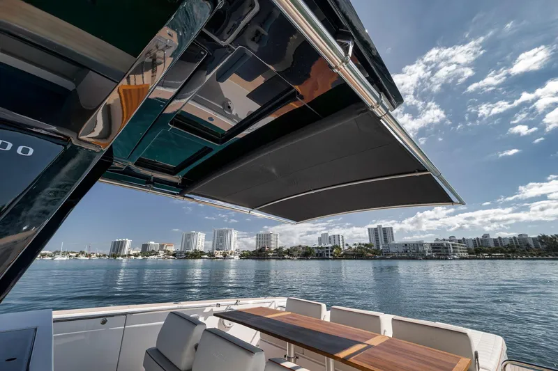 Slide: The Image of 2023 Pardo Yachts P43 with retractable awning, overlooking a coastal cityscape. - 17