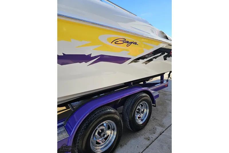 Slide: The Image of 2003 Baja 275 Boss boat with vibrant yellow and purple graphics on a trailer. - 22