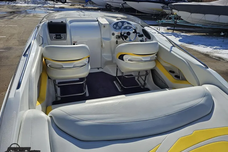 Slide: The Image of 2003 Baja 275 Boss boat interior with white and yellow seating, parked outdoors. - 44