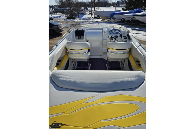 Slide: The Image of 2003 Baja 275 Boss boat interior with yellow and white seating, parked outdoors. - 48