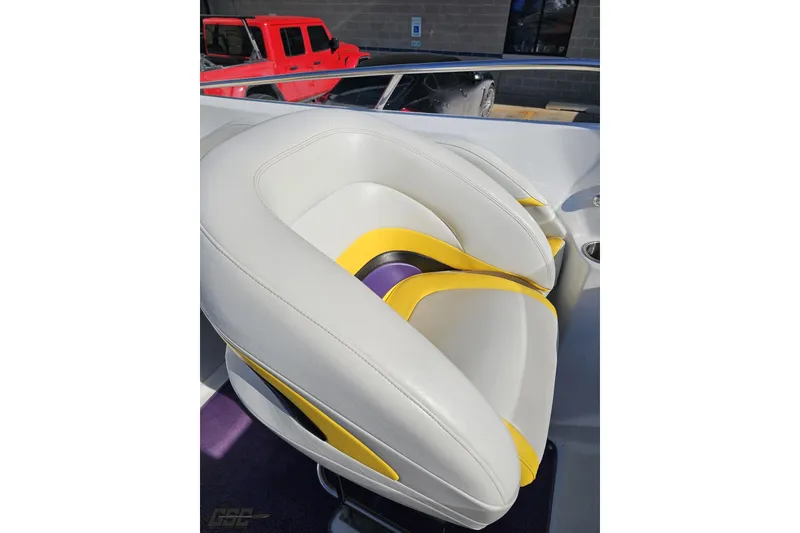 Slide: The Image of 2003 Baja 275 Boss boat seat with white and yellow design, parked red vehicle in background. - 62