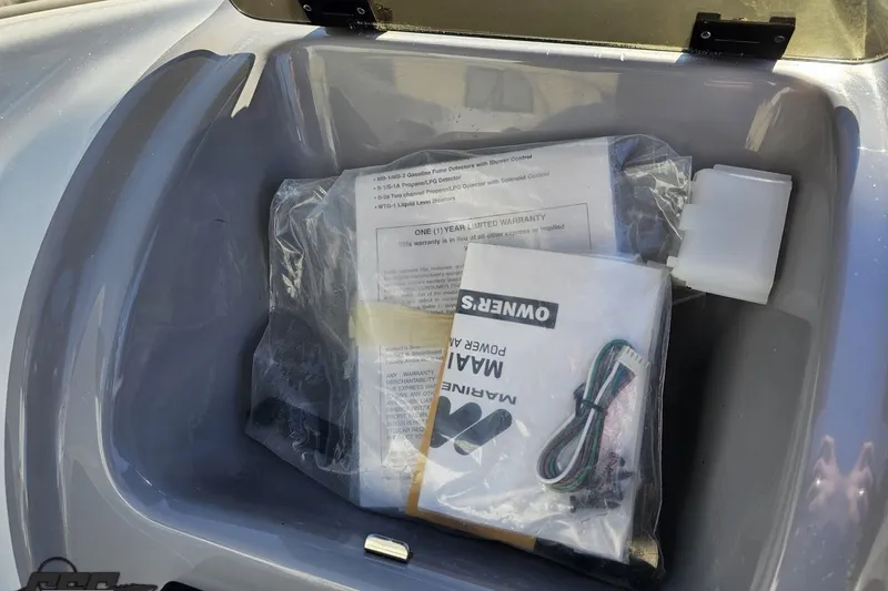 Slide: The Image of Storage compartment of a 2003 Baja 275 Boss boat with manuals and accessories. - 64