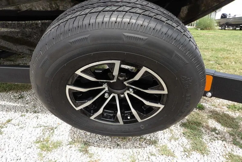Slide: The Image of 2025 Crestliner 1850 Fish Hawk Tiller trailer wheel on gravel surface. - 46