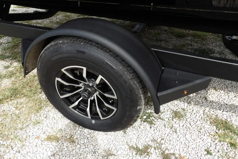 Slide: The Image of 2025 Crestliner 1850 Fish Hawk Tiller trailer wheel on gravel surface. - 47