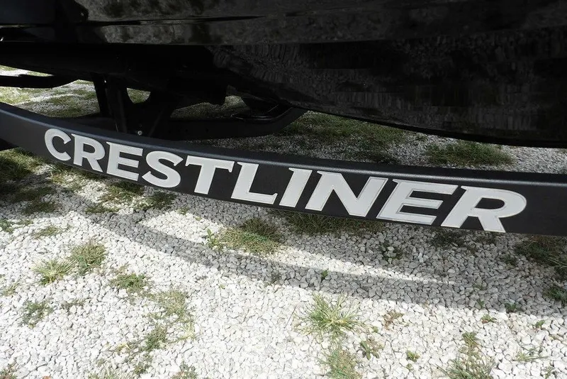 Slide: The Image of 2025 Crestliner 1850 Fish Hawk Tiller logo on boat trailer, gravel background. - 49