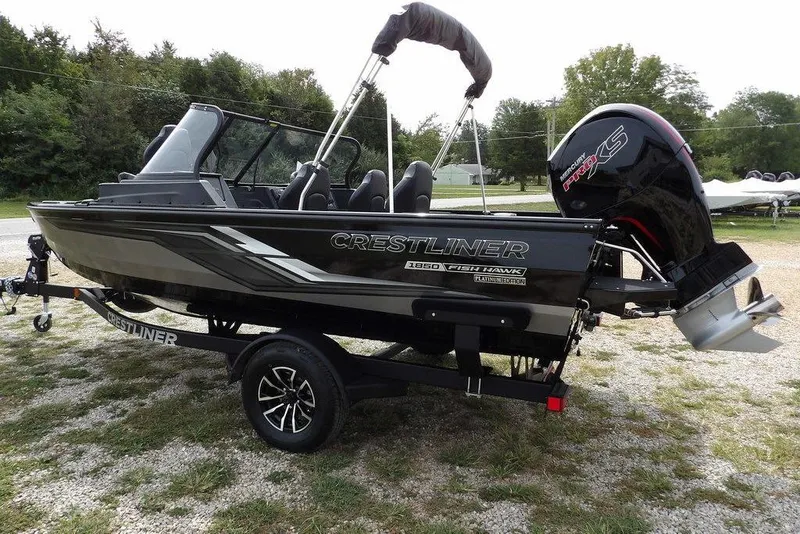 Slide: The Image of 2025 Crestliner 1850 Fish Hawk Tiller boat on trailer, parked outdoors. - 6