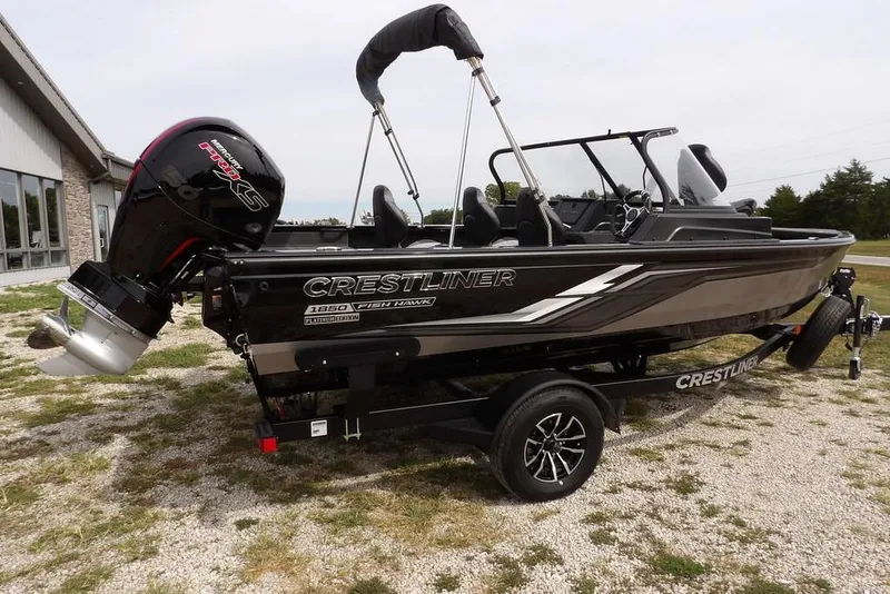 Slide: The Image of 2025 Crestliner 1850 Fish Hawk Tiller boat on trailer, outdoors, side view. - 7