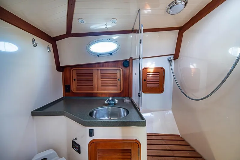 Slide: The Image of 2002 Hinckley Talaria 40 yacht interior with sink, wooden accents, and porthole window. - 13
