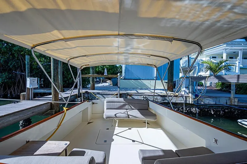 Slide: The Image of 2002 Hinckley Talaria 40 boat interior with canopy, docked near waterfront homes. - 16