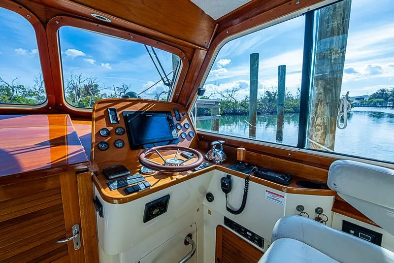 Slide: The Image of Helm of 2002 Hinckley Talaria 40 yacht with wooden dashboard and scenic water view. - 8