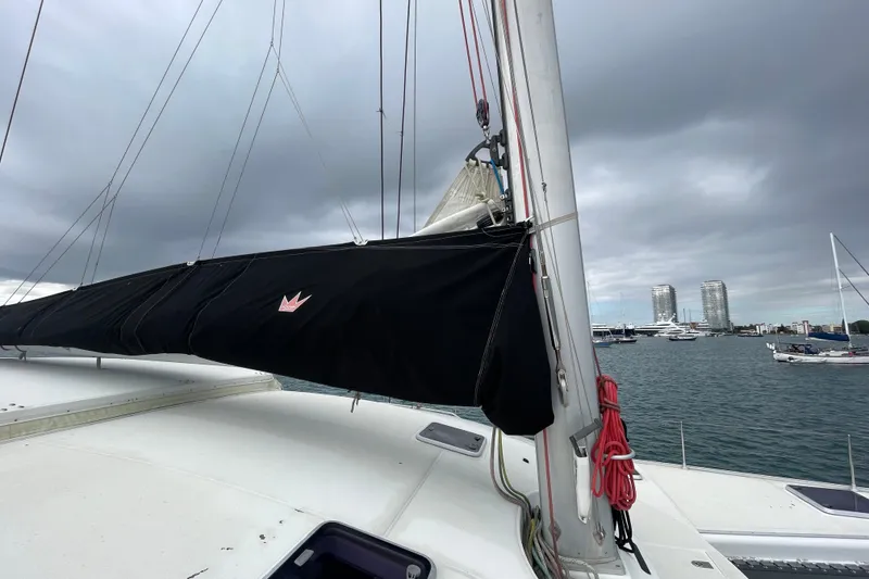 Slide: The Image of Sailboat Lagoon 570 (2004) with covered sail, docked in a marina under cloudy skies. - 13
