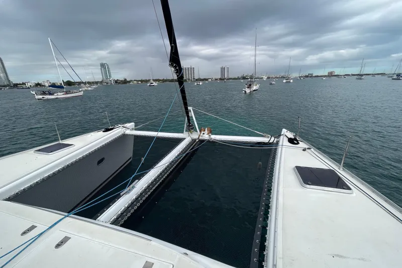 Slide: The Image of Lagoon 570 catamaran on water, overcast sky, city skyline in background, 2004 model. - 14