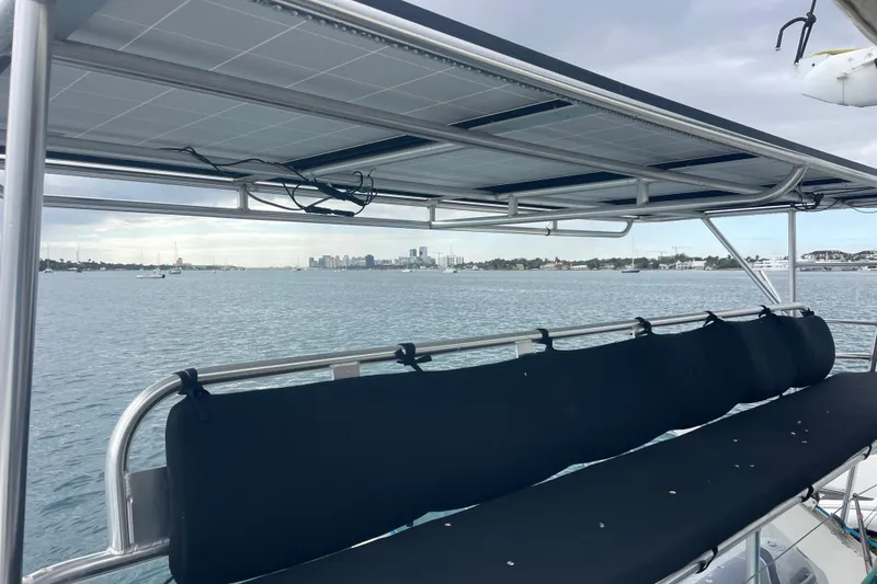 Slide: The Image of Lagoon 570 catamaran (2004) with solar panels, overlooking a coastal cityscape. - 18