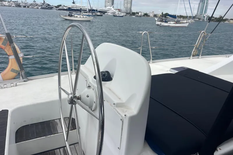 Slide: The Image of Steering wheel of 2004 Lagoon 570 yacht with ocean and boats in background. - 21