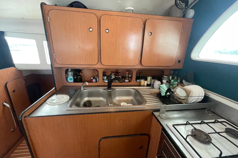 Slide: The Image of 2004 Lagoon 570 yacht kitchen with wooden cabinets, sink, and stove. - 35