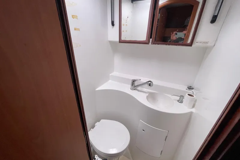 Slide: The Image of Compact bathroom in a 2004 Lagoon 570 yacht, featuring a sink, mirror, and toilet. - 42