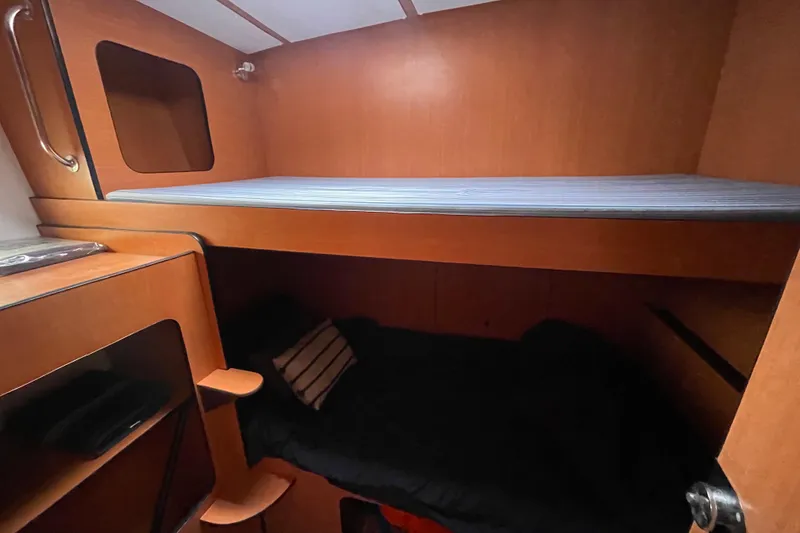 Slide: The Image of 2004 Lagoon 570 yacht interior with wooden bunk beds and storage shelves. - 44