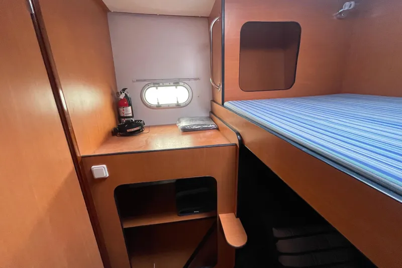 Slide: The Image of 2004 Lagoon 570 yacht cabin with wooden interior, bunk bed, and porthole window. - 45