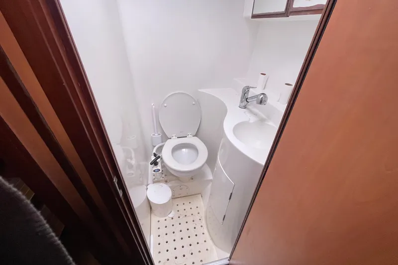 Slide: The Image of Compact bathroom in a 2004 Lagoon 570 yacht, featuring a toilet and sink. - 48