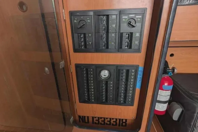 Slide: The Image of Electrical panel on a 2004 Lagoon 570 yacht with fire extinguisher nearby. - 64
