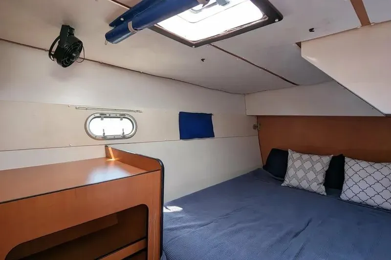 Slide: The Image of Cozy cabin interior of 2004 Lagoon 570 yacht with bed and porthole window. - 67