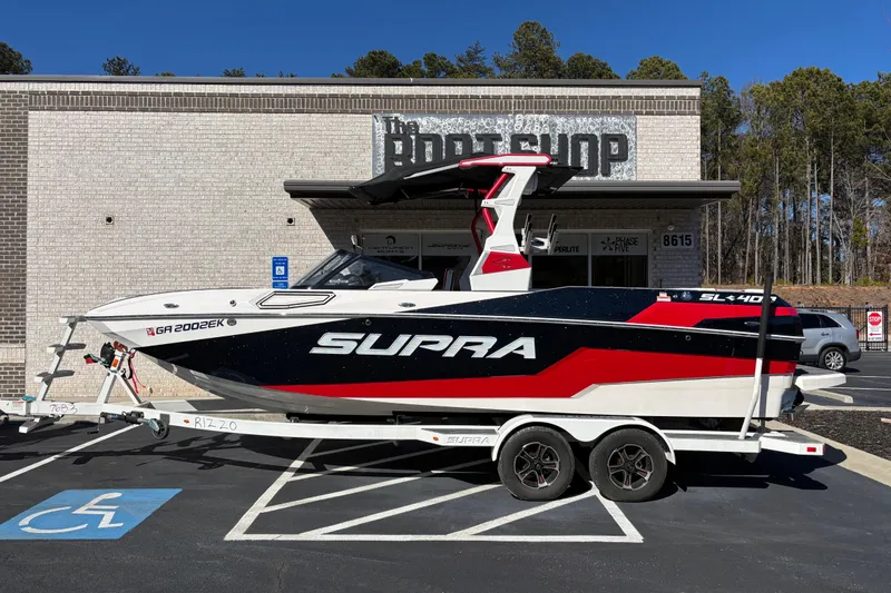 The Image of 2022 Supra SL 400 boat on trailer, parked outside a building, sunny day. - 0